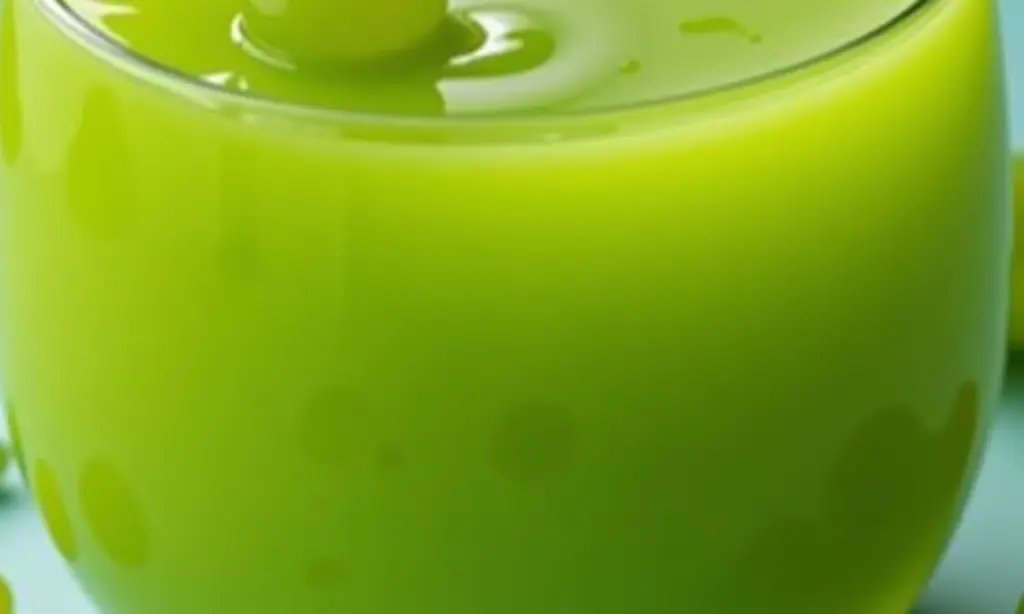 Copo de suco de uva verde fresco com uvas e folhas ao redor.